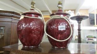 A pair of burgundy ceramic lamp base with oriental relief design.