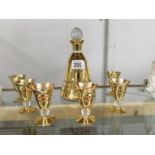 A gilded bell shaped liquor decanter and a set of 6 matching glasses.
