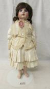 A porcelain headed doll in traditional costume with brown ringlets, 48 cm.