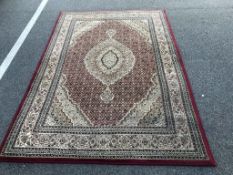 A large rug red and cream in colour 233cm x 160cm