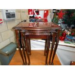 A dark wood stained nest of tables with red leather under glass tops 55cm x 42cm,