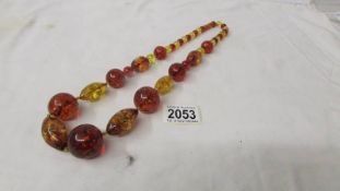 A long necklace of amber beads, reconstituted with 2 shades of amber yellow and burgundy.