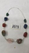 A multi gem necklace including Lapis, Agate, Rose Quartz and other gem stones on a silver chain.