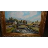 A gilt framed oil on board rural scene with stone bridge.