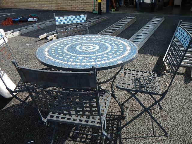 A metal garden table and chairs with tiled top.