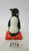 A Royal Doulton penguin standing on a book, in good condition.