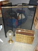 A brass candlelamp, a magazine rack and a fire guard with brass surround.