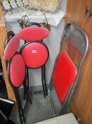 Three folding chairs with red covering.