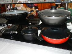 3 Woks with lids, a frying pan and a saucepan.