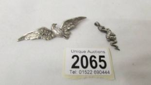A silver dragon pendant and a silver bird brooch.