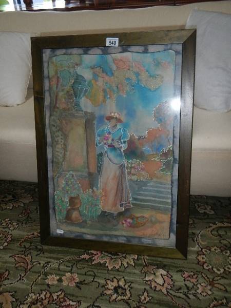 A framed and glazed picture of a lady with no face in a garden.