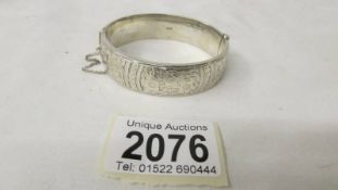 A silver bangle with chased work, hall marked Chester 1957.