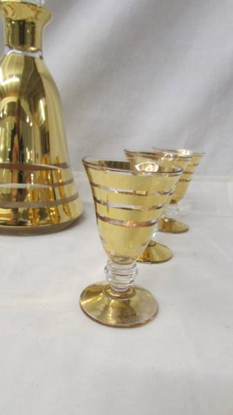 A mid 20th century gilded liquor decanter with 6 matching glasses. - Image 3 of 3