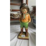 A painted plaster? model of a boy in waders and a fishing hat smoking a pipe on a square base with