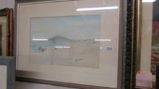 A framed and glazed watercolour coastal scene depicting fishermen unloading their catch in to a