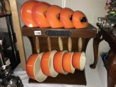 A set of 5 Le Crueset orange saucepans with lids & on stand