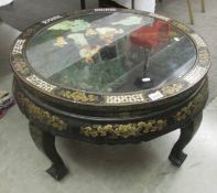 A circular Chinese lacquered coffee table with applied figures under glass top (collect only).