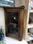 An oak corner cupboard with glass leaded door