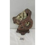 An oriental carved stone of figures in a rock, 14 cm wide x 18 cm high (not including base).