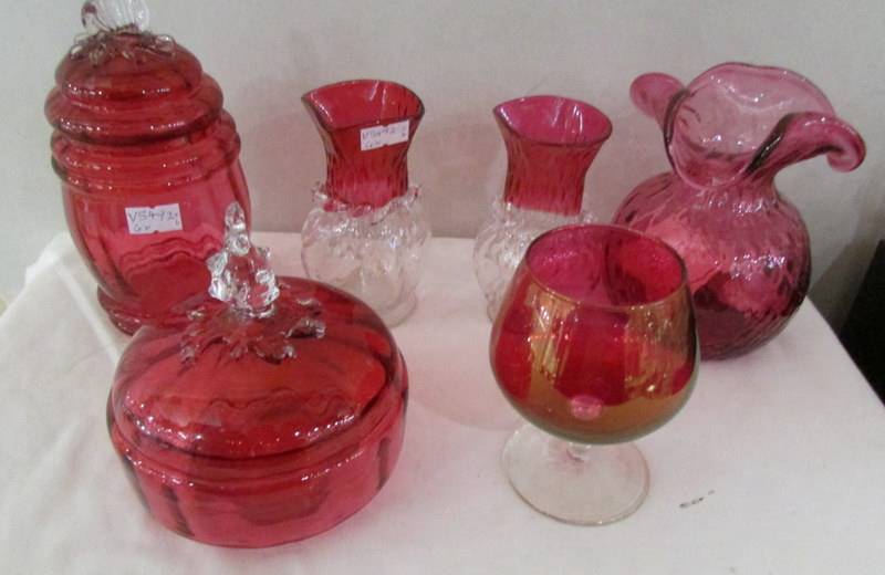 Six items of cranberry glass including pair of vases, single vase, lidded pot etc.