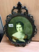 An oval metal framed portrait of a lady.