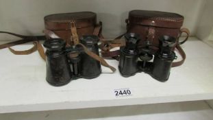 Two leather cased pair of early 20th century binoculars.