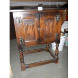 A two door oak cabinet with linen fold doors.