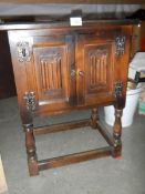 A two door oak cabinet with linen fold doors.