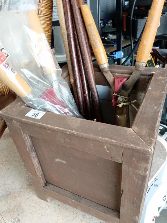 A cube wooden planter with a collection of walking sticks