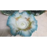 An 11" diameter satin glass bowl in pale blue with frilly rim and hand painted flowers including