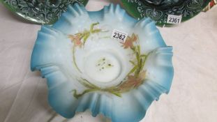 An 11" diameter satin glass bowl in pale blue with frilly rim and hand painted flowers including