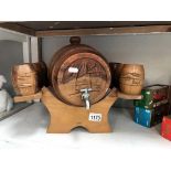 A carved teak brandy barrel on stand with drinking vessels