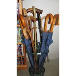 A green enamelled cast metal stick stand with umbrella's and walking sticks.