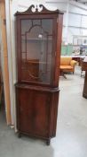 A dark wood stained corner cabinet with astragal glazed door.