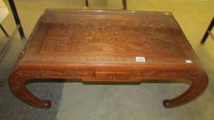 A heavily carved Chinese coffee table with glass top.