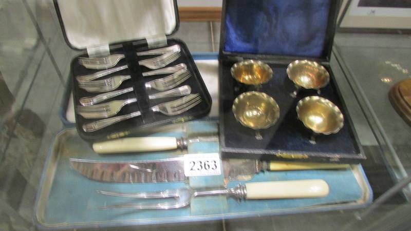 A cased set of 4 salts, a cased set of desert forks and a cased carving set.