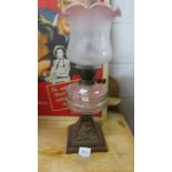 A Victorian oil lamp on cast iron base with glass font,