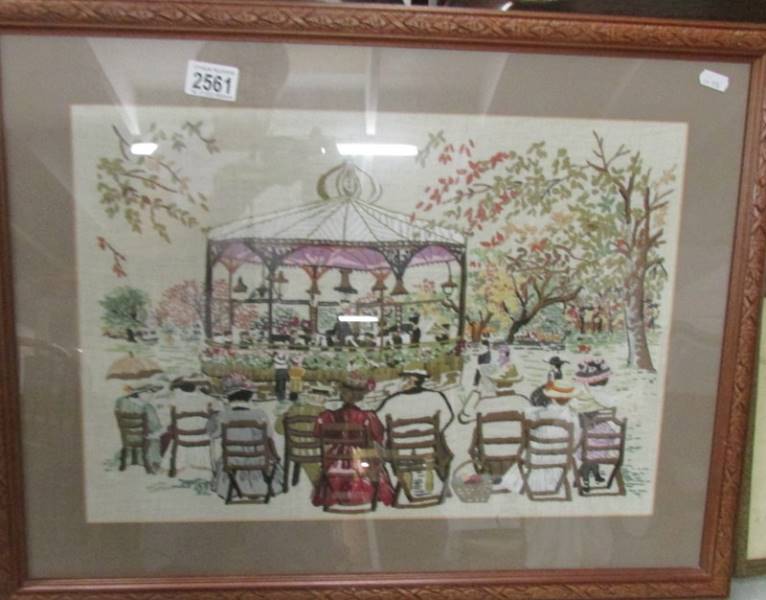 A framed and glazed embroidery depicting a Victorian band stand scene.