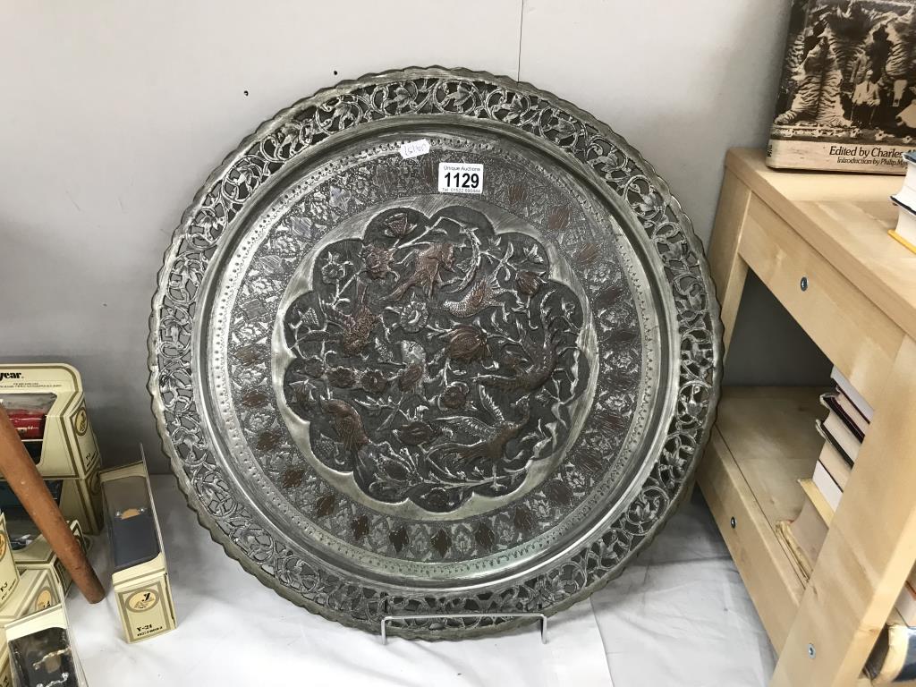 A large round Indian copper tray with relief decoration & silver plated finish
