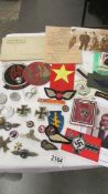 A selection of copies of German WW2 Nazi era badges etc., together with a quantity of cloth patches.