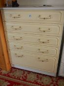 A five drawer white and cream bedroom chest.