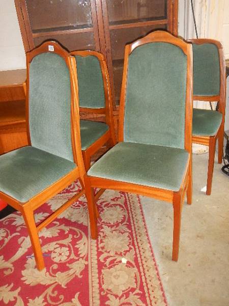 Two pairs of green covered dining chairs.