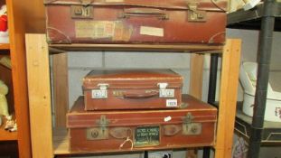 Three vintage leather suitcases, some with old travel labels.