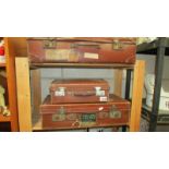 Three vintage leather suitcases, some with old travel labels.