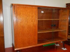A circa 1970's glass sliding door cabinet on turned tapered legs.