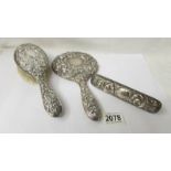 A silver backed hand mirror and two silver backed brushes, (one brush a/f).