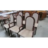 A set of six dark wood stained dining chairs with cream seats.