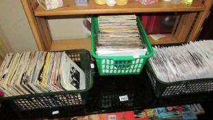 A quantity of 7" vinyls in 3 baskets including Simple Minds, Mike & the Mechanics.