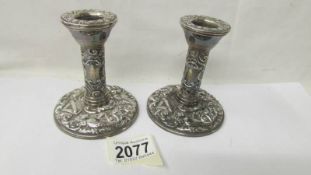 A pair of decorative silver candlesticks, 10 cm tall.