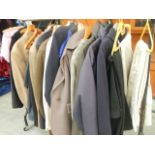 A rail of assorted suits, jackets and other clothing.